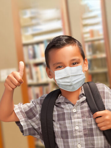 child smiles in front of book shelf