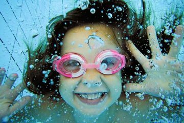 Girl underwater in pool with pink goggles