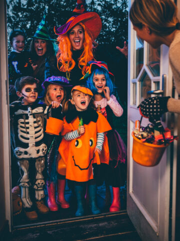 Halloween safety tips for families from CHOC - family in costume trick-or-treats at a neighbor's door