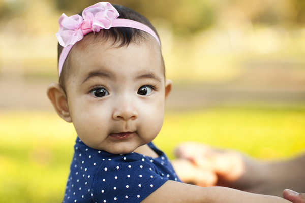 baby infant girl with pink bow and blue polka dots in mom's arms